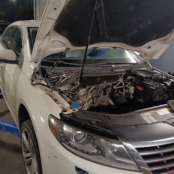 White sedan with the hood up inside a shop